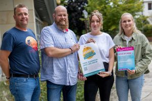 Carsten Kühl, Frank Weisemöller, Leonie Winter und Julia Schütte (von links) mit Hinweisplakaten auf die Schutzkonzepte, die beim Hollager Oktoberfest zum Einsatz kommen. Foto: Gemeinde Wallenhorst / André Thöle