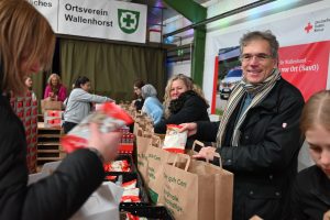 Packstraße in Wallenhorst: Zahlreiche ehrenamtliche Helferinnen und Helfer, hier mit Regionalbischof Friedrich Selter (rechts), packten die Tüten mit Zutaten für Weihnachtskekse und Pflegeprodukte. Foto: Urte Tegtmeyer