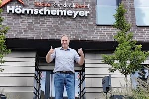 Maik Peschke vor dem Firmenschild „Hörnschemeyer Dächer“. Foto: Lisa Kundetov