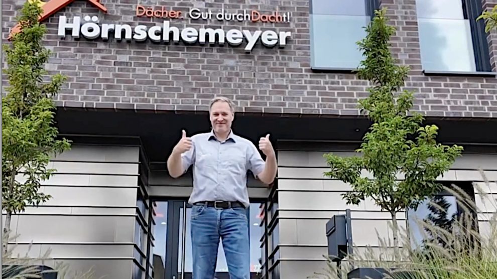 Maik Peschke vor dem Firmenschild „Hörnschemeyer Dächer“. Foto: Lisa Kundetov